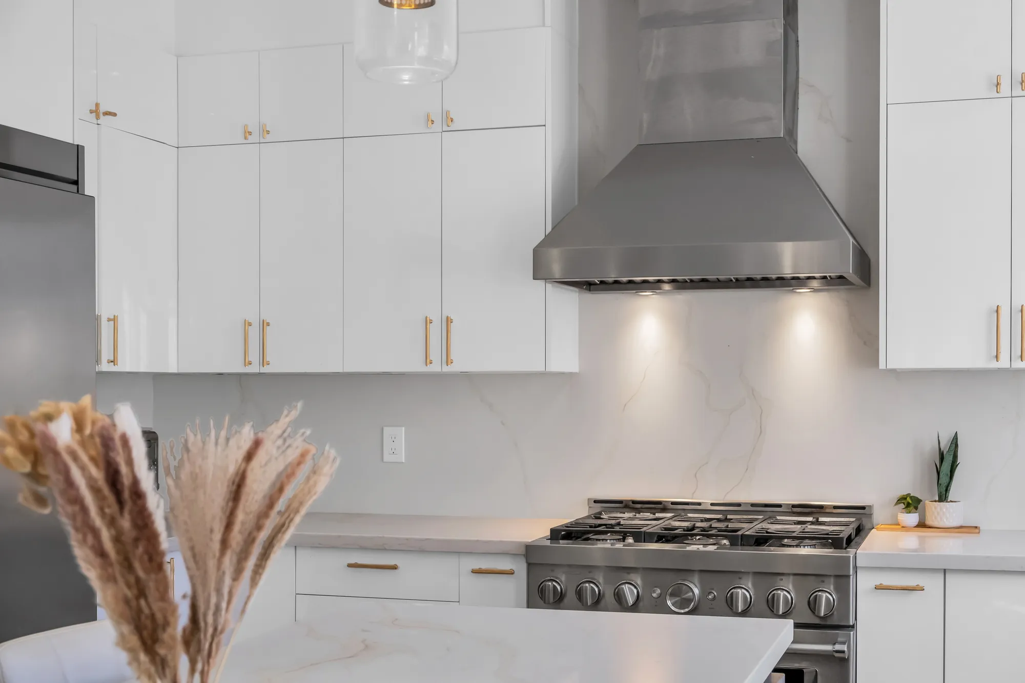 A close view of the gas range and the hood, white cabinets above