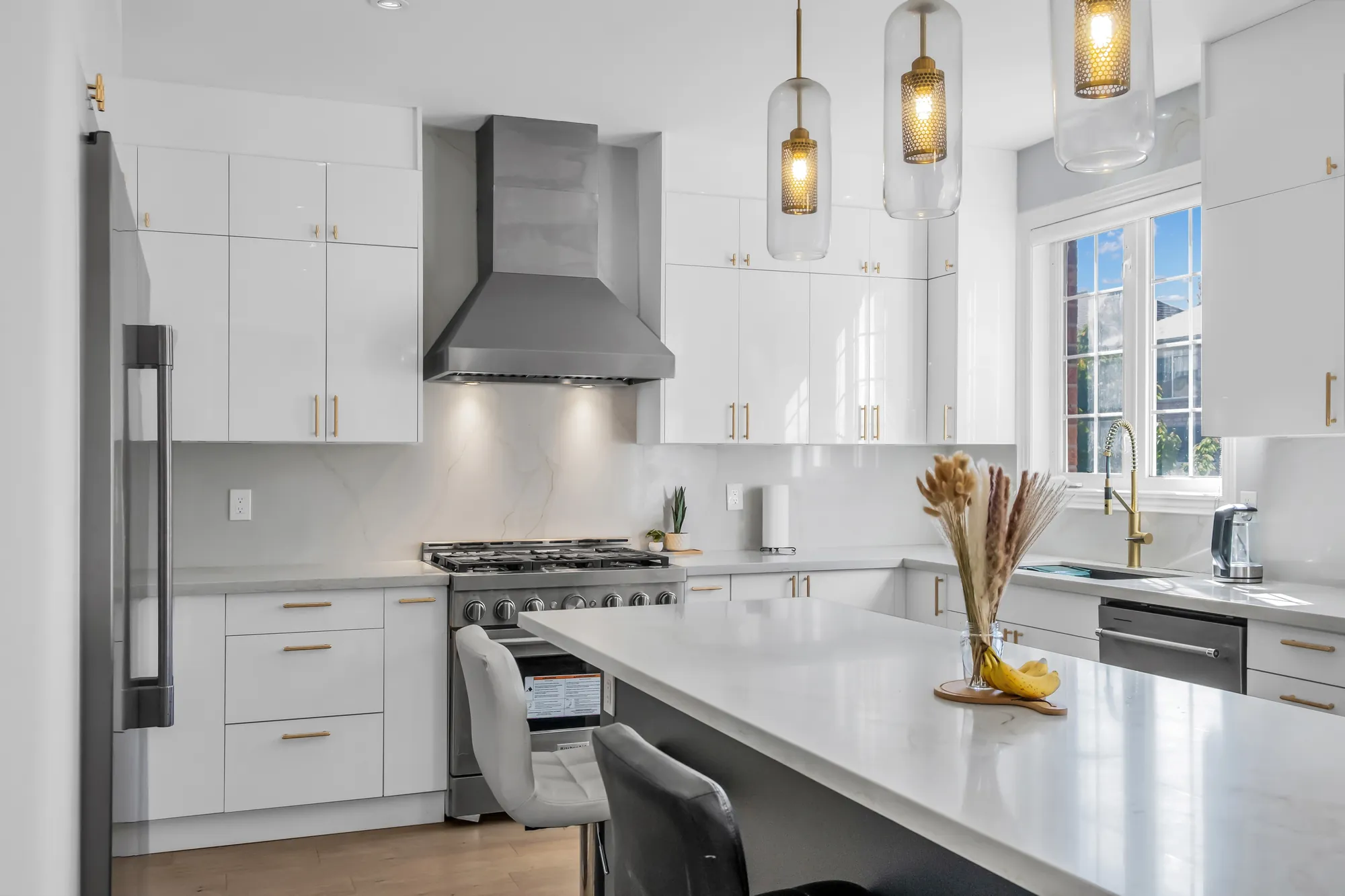 The island and the range toward the window over the sink, the glass pendants overhead